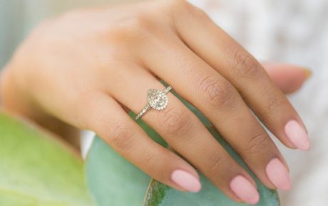 2 carat pear diamond ring on hand with halo ring design