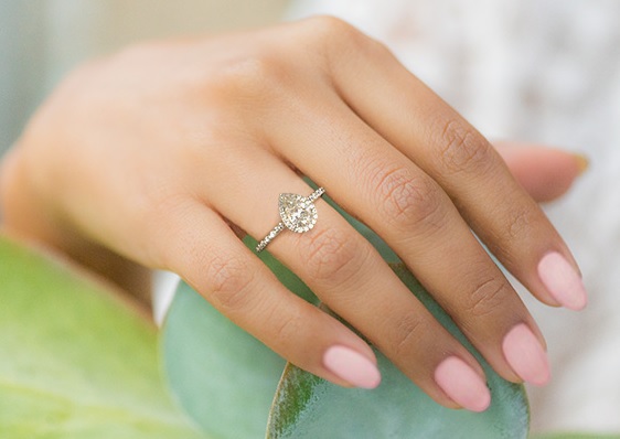 2 carat pear diamond ring on hand with halo ring design